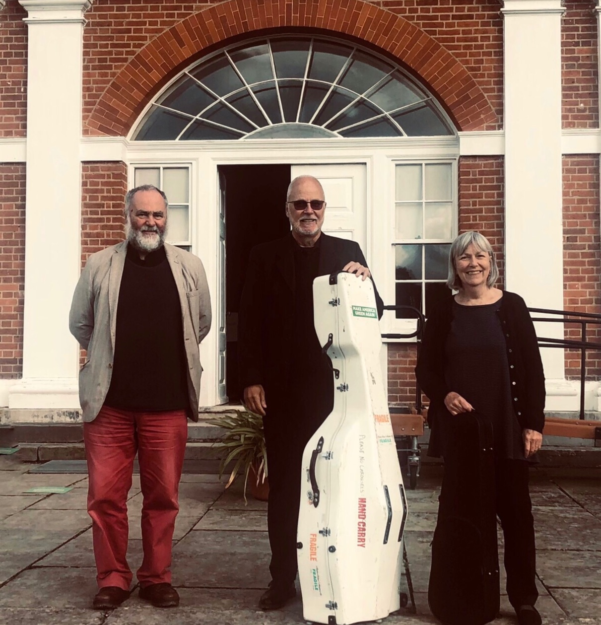 3 members of Geminiani Ensemble standing in front of concert venue, smiling